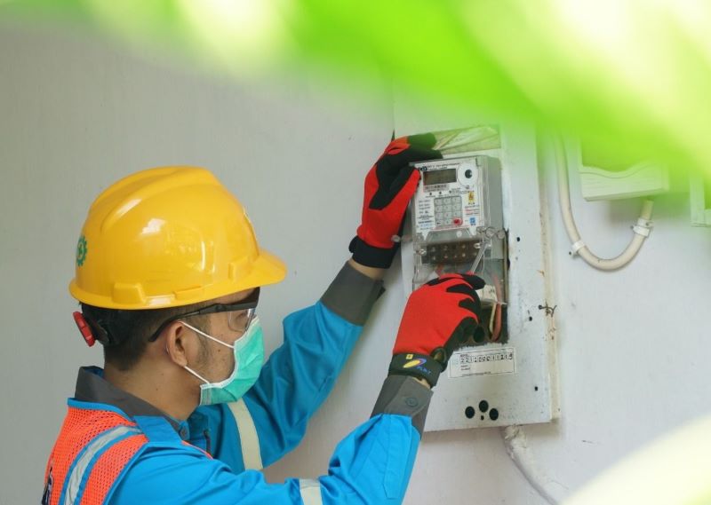 Ilustrasi petugas PLN saat menyesuaikan Miniature Circuit Breaker (MCB) pada kWh meter pelanggan yang membutuhkan layanan penyambungan listrik sementara. (dok. rentak.id)